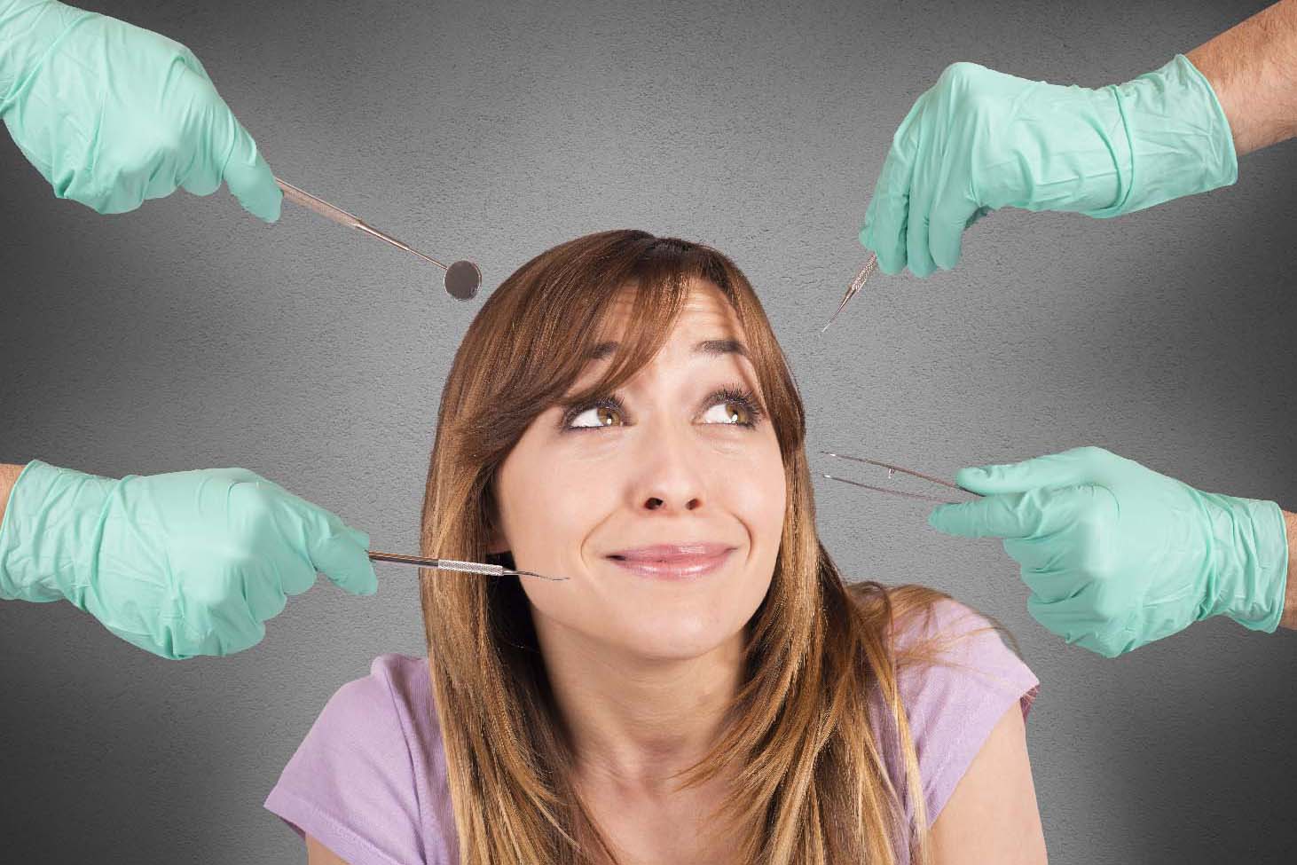 Woman surrounded by dental instruments looking afraid